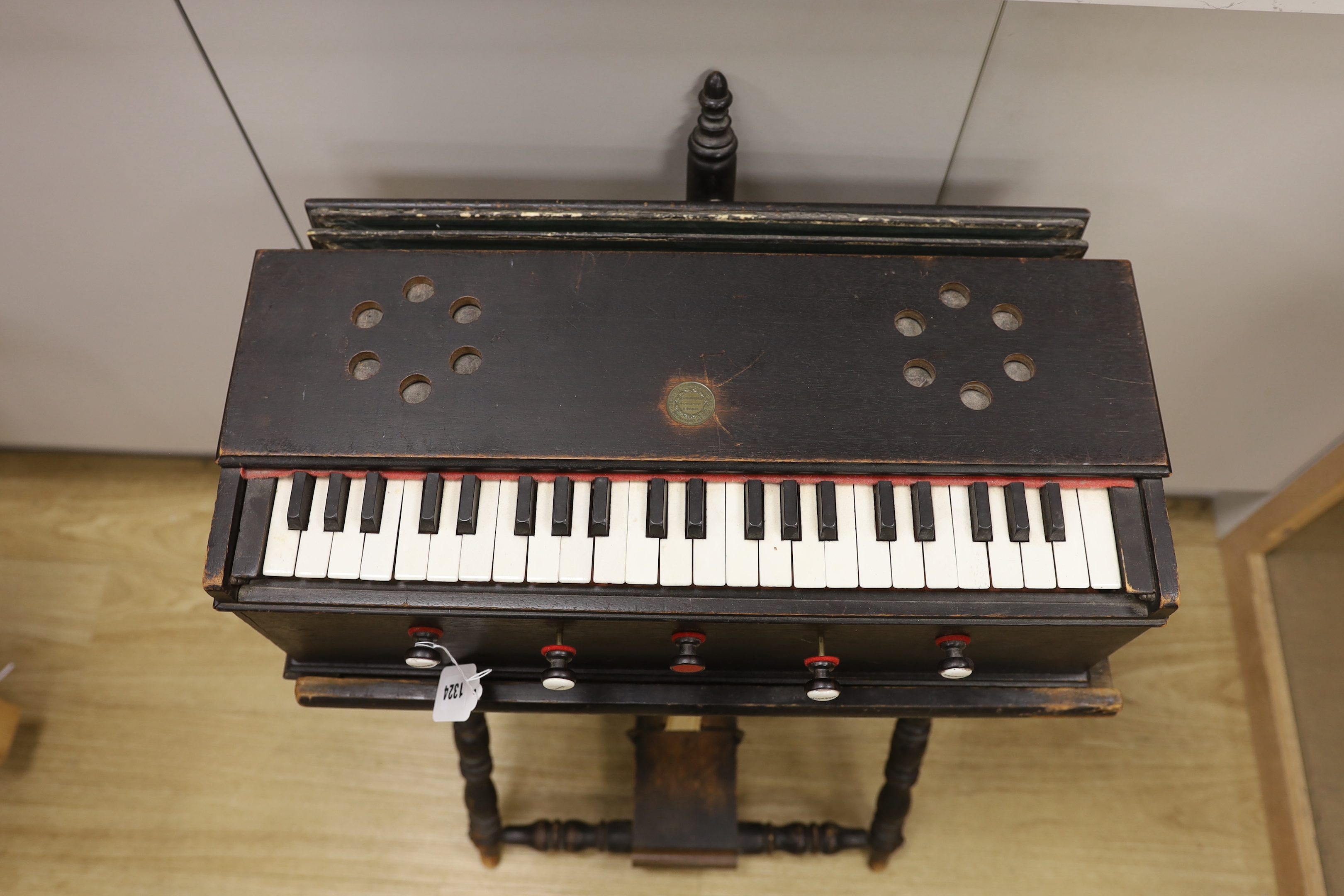 An Indian single bellow portable harmonium, with turned ebonised stand and foot pedal, 75.5cm high, 54.5cm wide
